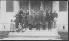 SA0153 - Fourteen men and women, along with two children, in front of a meeting house; men are on one side, women on the other.